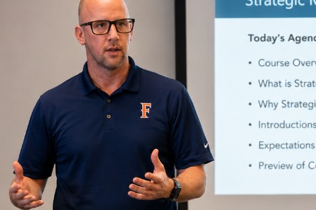 Photo of Dan Nannery teaching, mid-gesture, wearing a Cal State Fullerton polo